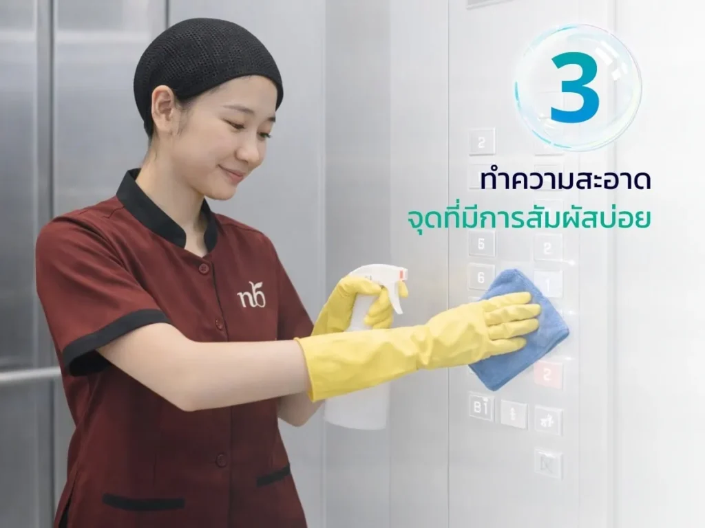 พนักงานทำความสะอาดกำลังเช็ดปุ่มลิฟต์ซึ่งเป็นจุดสัมผัสบ่อย ด้วยน้ำยาและผ้า เพื่อรักษาความสะอาดและสุขอนามัยในอาคารสำนักงาน